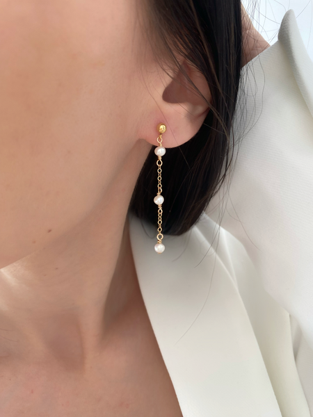 Les boucles PERLA, incarnent féminité et romantisme. Ces boucles d'oreilles délicates, réalisées en or laminé 585/1000* (Gold filled), se distinguent par l'harmonie de leurs trois perles d'eau douce, qui ajoutent une note de douceur et de poésie à chaque tenue