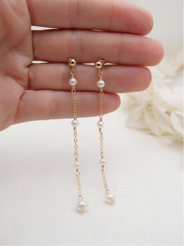 Les boucles PERLA, incarnent féminité et romantisme. Ces boucles d'oreilles délicates, réalisées en or laminé 585/1000* (Gold filled), se distinguent par l'harmonie de leurs trois perles d'eau douce, qui ajoutent une note de douceur et de poésie à chaque tenue