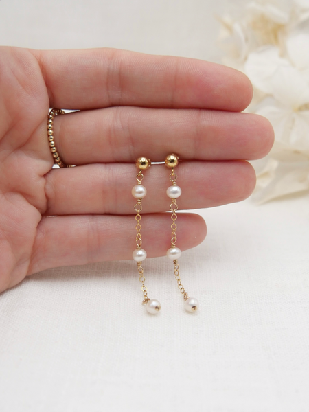 Les boucles PERLA, incarnent féminité et romantisme. Ces boucles d'oreilles délicates, réalisées en or laminé 585/1000* (Gold filled), se distinguent par l'harmonie de leurs trois perles d'eau douce, qui ajoutent une note de douceur et de poésie à chaque tenue